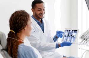 Black man dentist and woman patient looking at xray picture