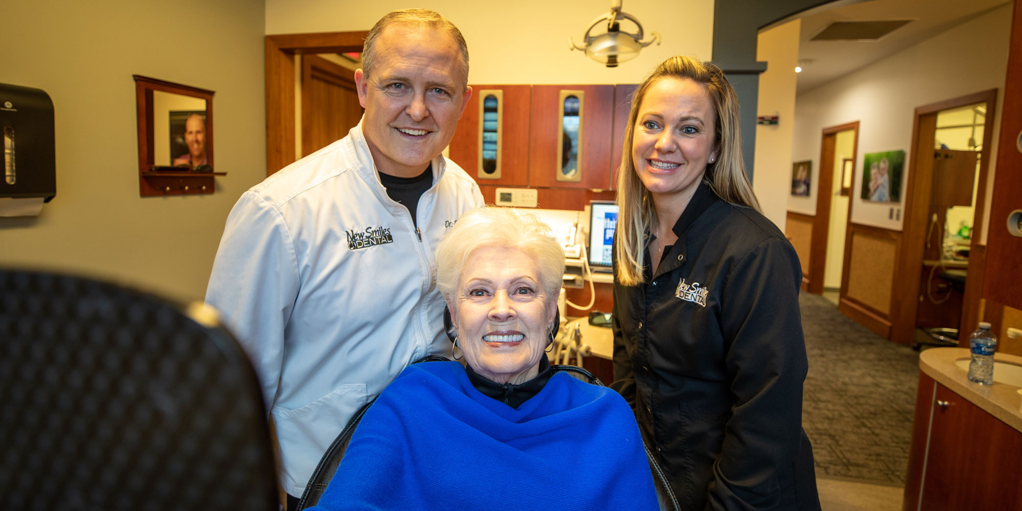 Dr. Nathan Doyel and staff member smiling with a dental patient after her dental implant procedure