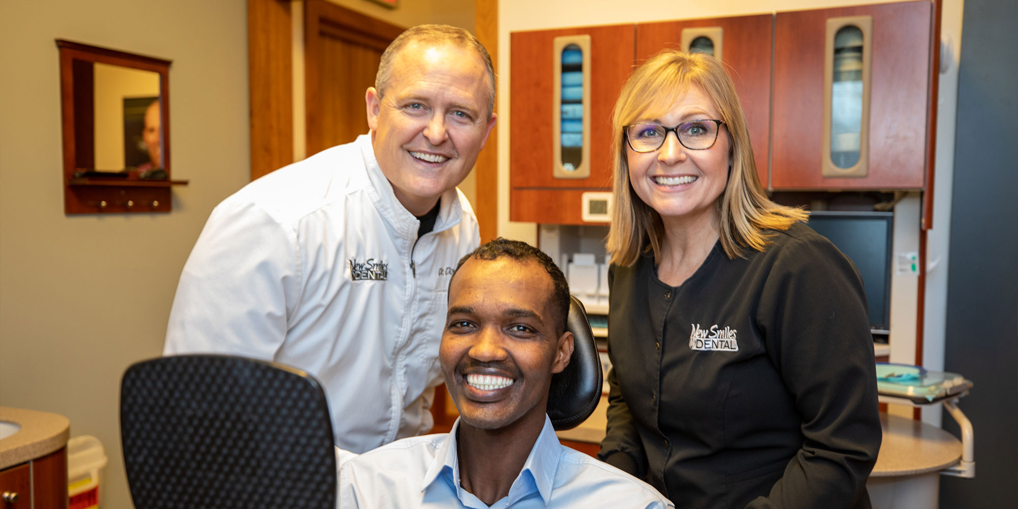 Patient and staff member and doctor smiling after dental procedure
