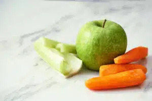 green apple carrots and celery on marble background